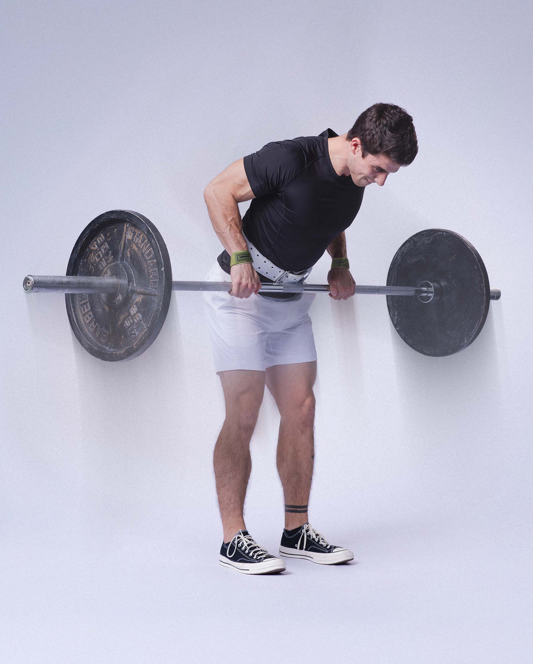 man doing barbell rows with uppper lifting straps and lifting belt